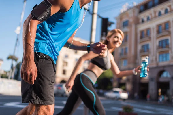 Deportiva y deportista trotando en la ciudad - foto de stock