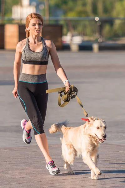 Sportswoman jogging with dog — Stock Photo