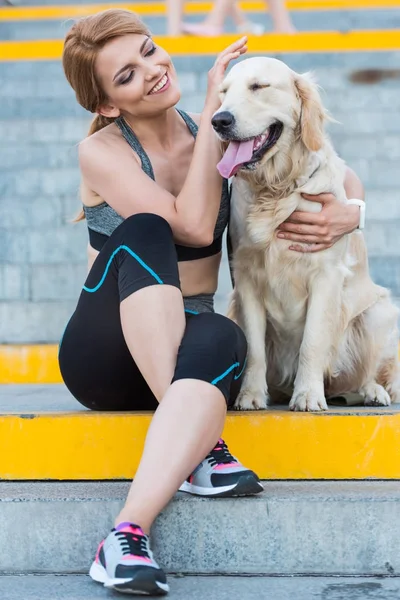 Спортсменка сидить з собакою — стокове фото