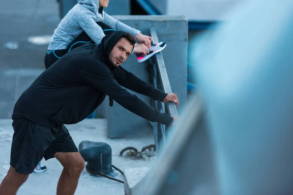 Sportswoman and sportsman stretching in city — Stock Photo