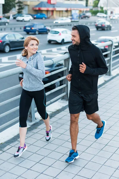 Sportswoman and sportsman jogging in city — Stock Photo