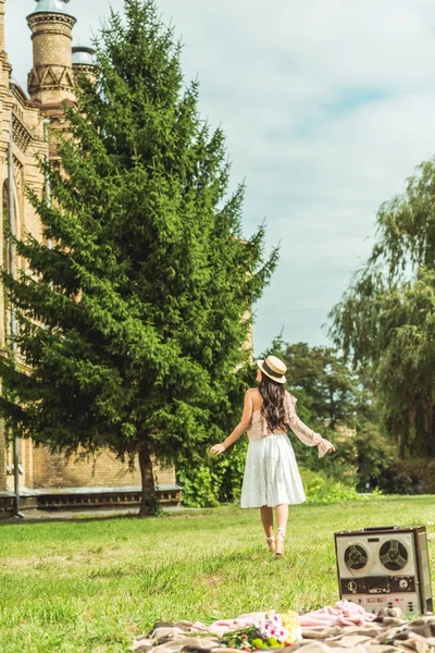 Стильна дівчина в солом'яному капелюсі в парку — стокове фото