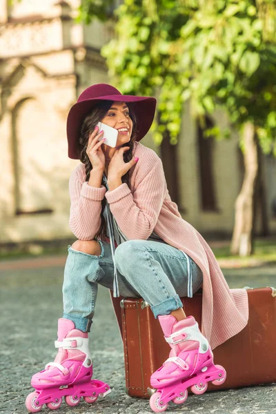 Девушка в роликовых коньках со смартфоном и чемоданом — стоковое фото