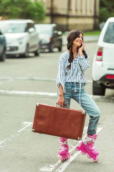 Girl in roller skates with smartphone and suitcase — Stock Photo