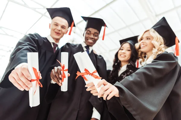 Studenti multietnici che mostrano diplomi — Foto stock