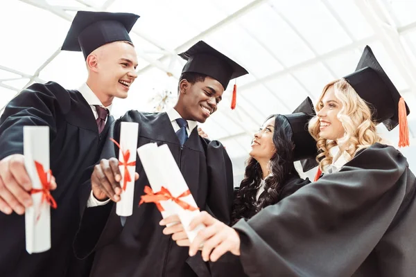 Studenti multietnici che mostrano diplomi — Foto stock