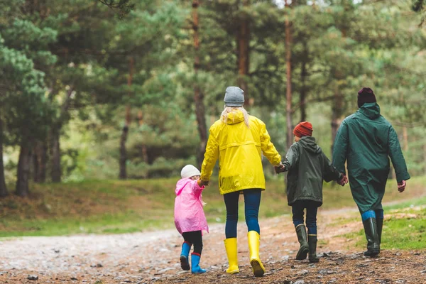 Família em capas impermeáveis andando na floresta — Fotografia de Stock