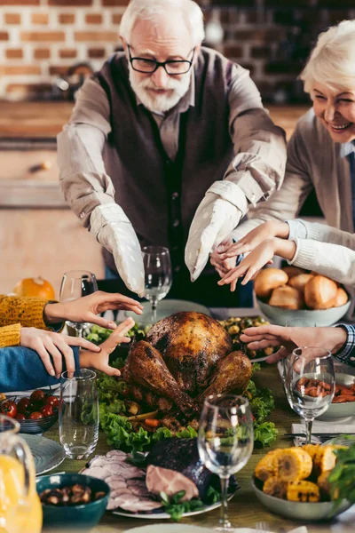 Grandparents and family reaching for turkey — Stock Photo