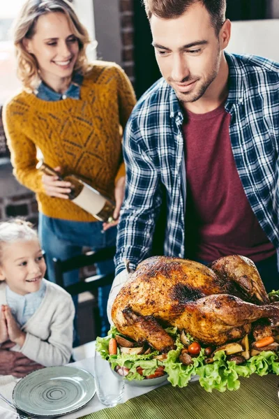 Father putting turkey on holiday table — Stock Photo