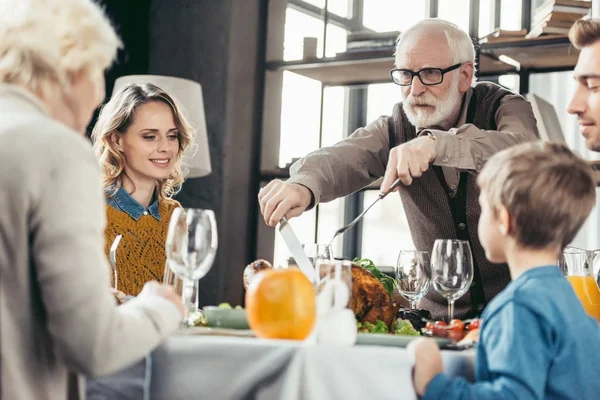Grandfather cutting turkey for family — Stock Photo