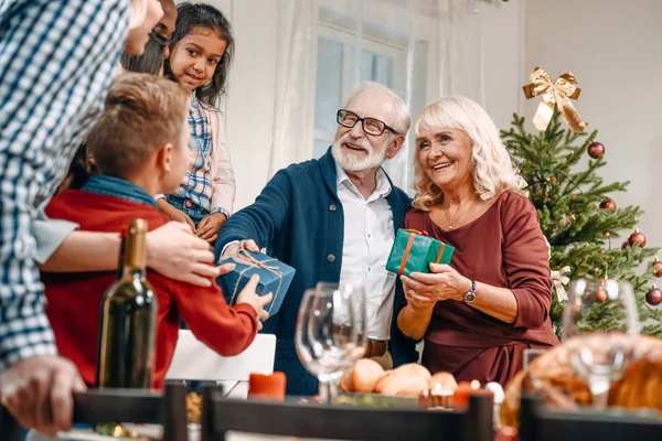 Grandparents presenting christmas gifts to kids — Stock Photo