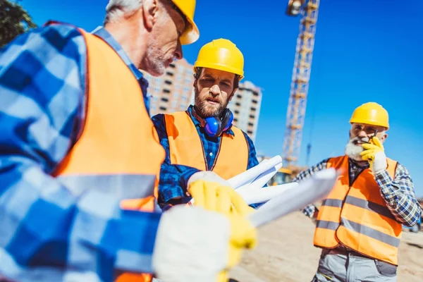 Trabajadores de la construcción examinando plan de construcción - foto de stock