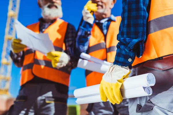 Trabajadores de la construcción con planos de construcción - foto de stock