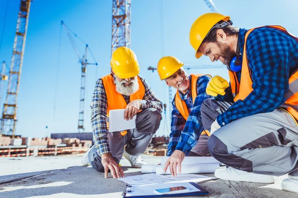 Trabalhadores da construção discutindo planos de construção — Fotografia de Stock