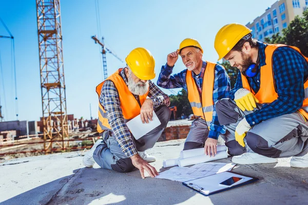 Trabalhadores da construção civil com planos de construção — Fotografia de Stock