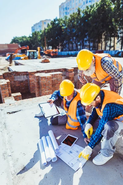 Trabalhadores da construção que examinam planos de construção — Fotografia de Stock