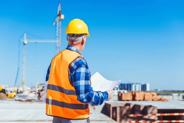 Trabajadores de la construcción con planos de construcción - foto de stock