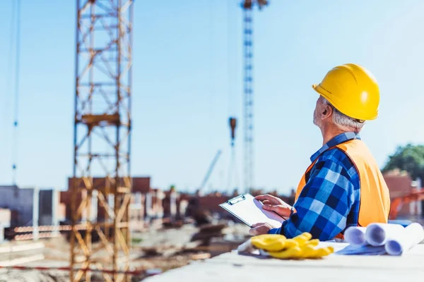 Construction worker writing on clipboard — Stock Photo