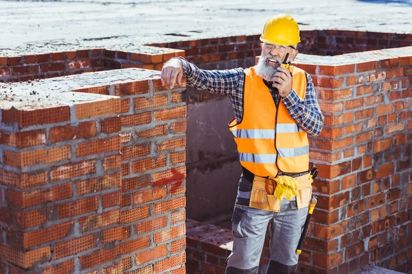 Trabajador de la construcción hablando por radio portátil - foto de stock