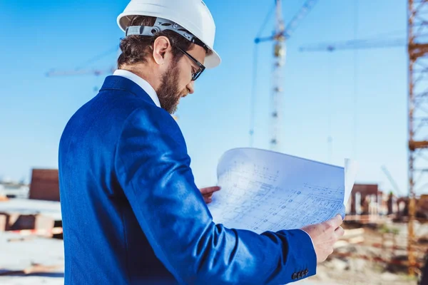 Empresário em hardhat leitura de planos de construção — Fotografia de Stock