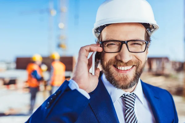 Businessman talking on phone at construction site — Stock Photo