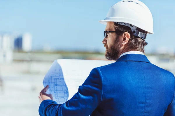 Homme d'affaires en casque dur examinant les plans de construction — Photo de stock