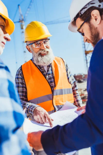 Construtores e empresário discutindo planos de construção — Fotografia de Stock