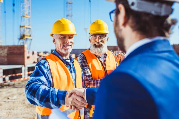 Obrero de la construcción y empresario estrechando la mano - foto de stock