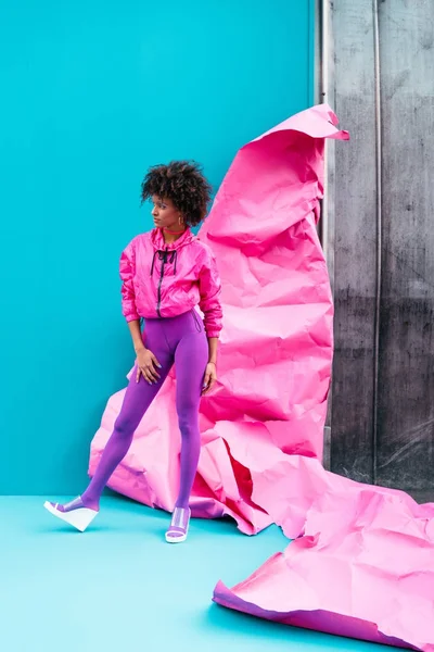 Fashionable african american pising at pink paper — Stock Photo