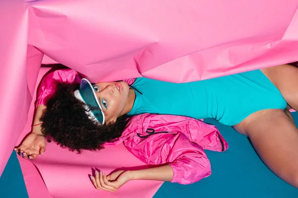 Modèle afro posant avec du papier rose — Photo de stock