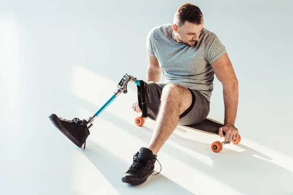 Homme avec prothèse de jambe assis sur skateboard — Photo de stock