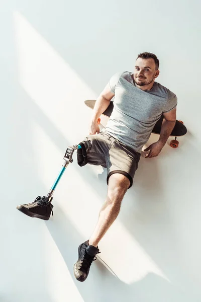 Uomo con protesi alle gambe appoggiato sullo skateboard — Foto stock