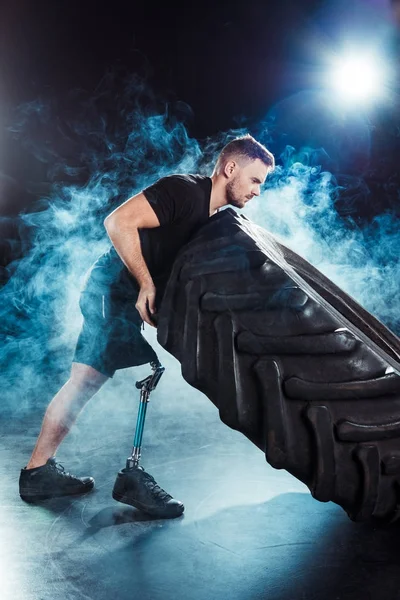 Спортсмен-паралимпиец тянет шину — стоковое фото