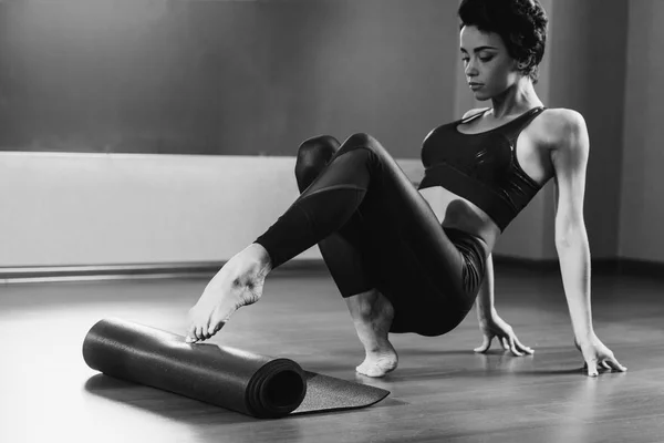 Mulher rolando tapete de ioga — Fotografia de Stock