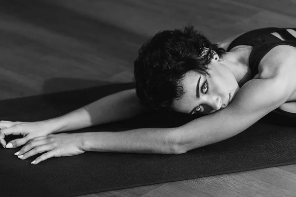 Mujer deportiva que pone en la estera de yoga - foto de stock