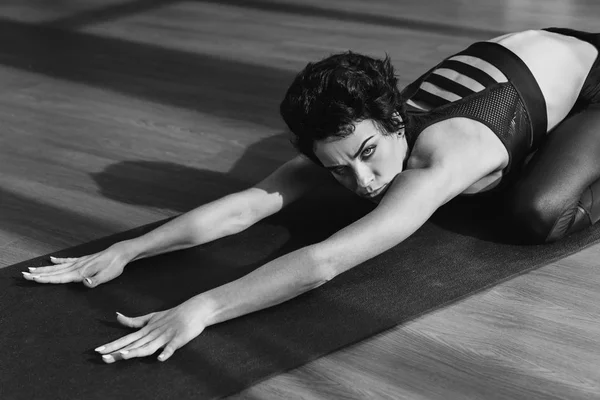Mulher se alongando no tapete de ioga — Fotografia de Stock