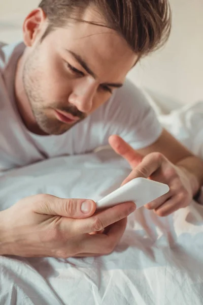 Человек с помощью смартфона в постели — стоковое фото