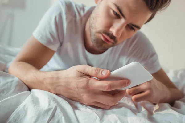 Человек с помощью смартфона в постели — стоковое фото