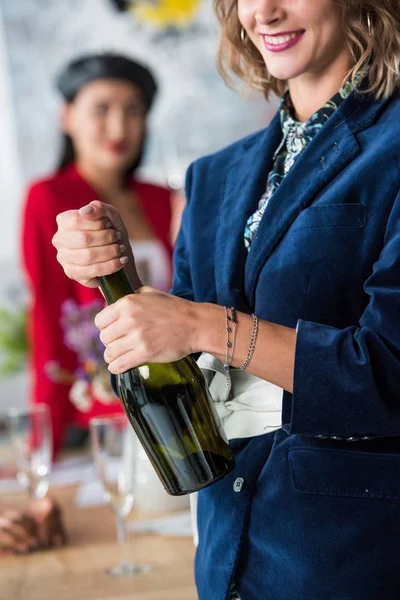 Mujer apertura botella de champán - foto de stock