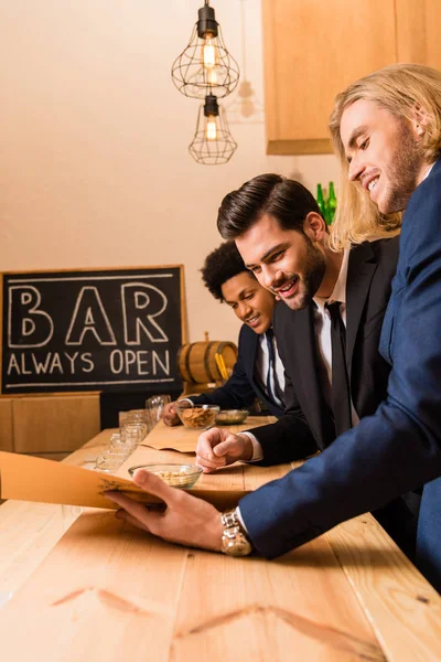 Hombres de negocios con menú en bar - foto de stock