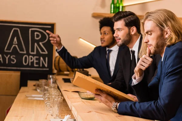 Businessmen with menu in bar — Stock Photo