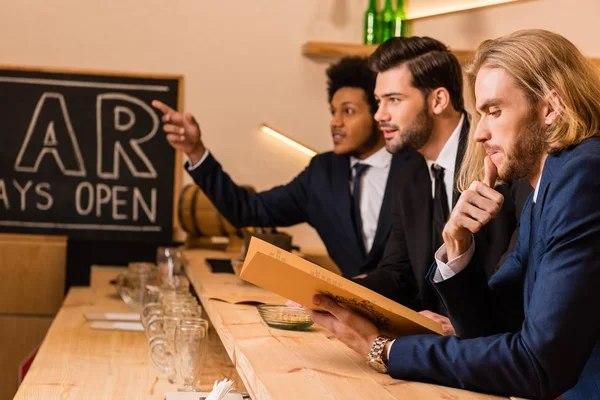 Hombres de negocios con menú en bar - foto de stock