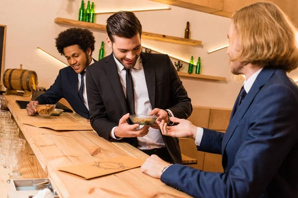 Hombres de negocios comiendo bocadillos en el bar - foto de stock