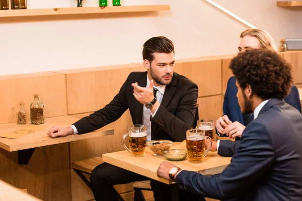 Hombres de negocios bebiendo cerveza en el bar - foto de stock
