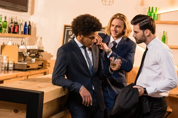Hombres de negocios bebiendo whisky en el bar - foto de stock