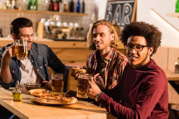 Amici con pizza e birra al bar — Foto stock