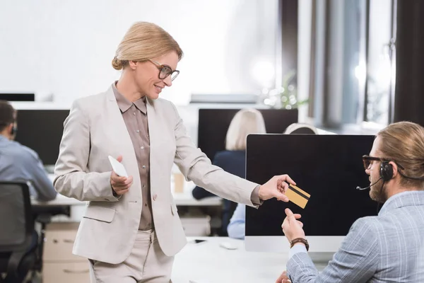 Donna d'affari che dà carta di credito al collega — Foto stock