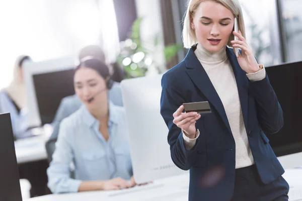 Empresária com cartão de crédito falando no smartphone — Fotografia de Stock