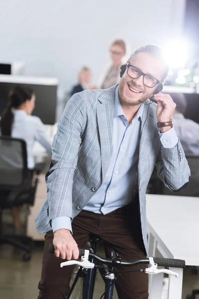 Call center operator in headset on bicycle — Stock Photo