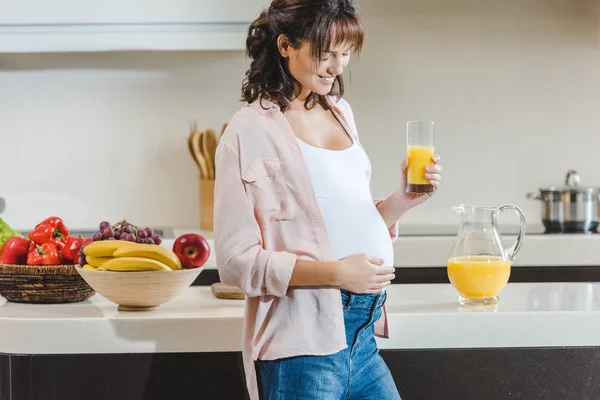 Mujer embarazada con jugo tocando el vientre - foto de stock